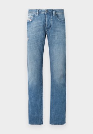 Vaaleansiniset farkut suorilla lahkeilla, joissa on napillinen vetoketju, viisi taskua ja hienovaraiset ompeleiden yksityiskohdat takataskuissa.