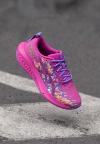 Ροζ αθλητικό παπούτσι με υφασμάτινη πλέξη, μοβ λεπτομέρειες και πολύχρωμο, αφηρημένο σχέδιο στις πλαϊνές επιφάνειες. Ελαφρύ σχέδιο με κορδόνια.