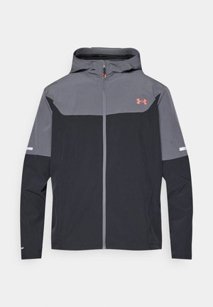 Fekete és szürke cipzáros kapucnis dzseki. Elegáns kialakítású, könnyű anyagból készült, élénk narancssárga logóval a mellrészen. Reflektáló részletekkel.