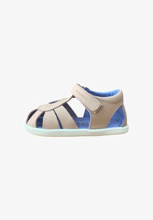Sandalia beige de cuero para niños pequeños con interior acolchado azul, cierre de velcro, diseño de punta abierta y suela de goma blanca.