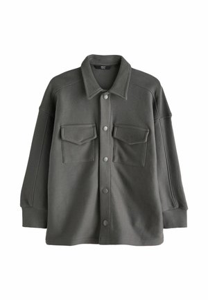 Dark grey oversized button-up shirt made of soft fabric, featuring two front pockets, a pointed collar, and snap buttons.