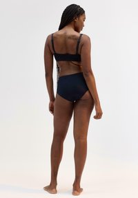 Svart bralette och matchande högmidjade trosor, tillverkade av mjukt tyg, med justerbara band och minimalistisk design.
