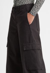 Zwarte cargobroek van katoen met een relaxed fit, voorzien van zijzakken en zichtbare stiksels op de zakken en de tailleband.