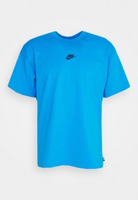 Blå bomull t-shirt med kort ärm, rund hals, har en svart Nike-logga på bröstet. Enkel, enfärgad design, mjuk textur.