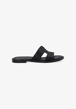 Zwarte platte sandalen van leer met twee overlappende bandjes en uitsnijdingen. Glad oppervlak en minimalistisch ontwerp.
