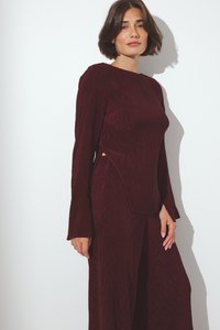 Top con maniche lunghe e colletto alto, realizzato in tessuto a coste di color bordeaux; presenta ritagli laterali e una vestibilità rilassata. Pantaloni larghi in abbinamento.