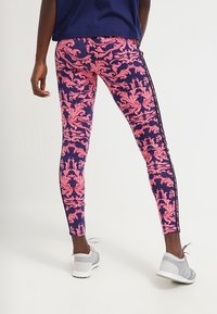 Legíny s námořnickým základem, s růžovým květinovým vzorem, vyrobené z elastického materiálu, se slim fit střihem a černým bočním pruhem.