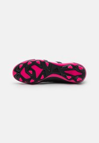 Scarpe Adidas con suola nera e rosa caratterizzata da tacchetti triangolari e dettagli testurizzati per trazione e supporto.