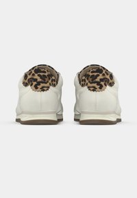 Λευκά αθλητικά παπούτσια με καφέ σόλες, διακοσμημένα με λεοπάρ μοτίβο στη φτέρνα. Λείο υλικό με στρογγυλεμένο σχήμα και χαμηλό προφίλ σχεδίασης.