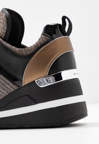 Schwarze und bronzene Sneaker mit einer strukturierten Stoffoberfläche, glänzenden Akzenten und einer dicken, weiß-schwarzen Sohle mit einem glänzenden Fersendetail.