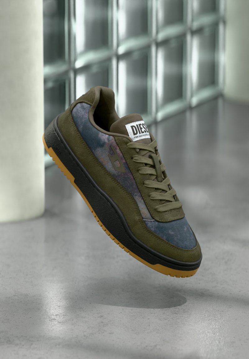 Scarpa da ginnastica verde oliva con tomaia in camoscio e tessuto, suola nera e dettagli in gomma. Presenta un logo sulla linguetta e un design strutturato.