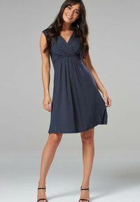 Navy blue, knee-length dress with a V-neck and cap sleeves. Features a twist detail at the waist and white polka dots on a textured fabric.