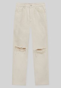 Beigen värisiä farkkuja suorilla lahkeilla, joissa on kaksi suurta kulutuksen aiheuttamaa repeämää polvilla ja perinteinen viiden taskun muotoilu.