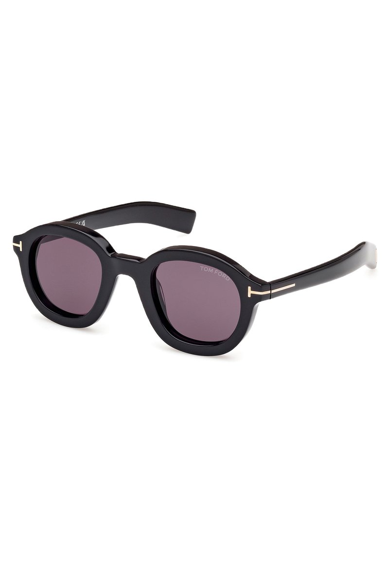 Lunettes de soleil noires avec des montures ovales, verres violets et accents dorés sur les branches. Fabriquées en plastique brillant avec une texture lisse.
