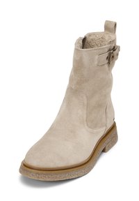Beige suède enkellaarsje met een licht gestructureerd oppervlak, ronde neus en een kleine, gestapelde hak. Voorzien van een verstelbare band met metalen hardware.