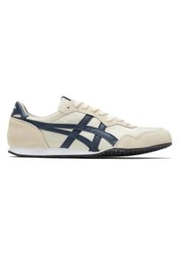 Chaussure de sport profil bas beige avec des rayures bleu foncé et une semelle blanche, avec des accents en daim au talon et à l’avant.