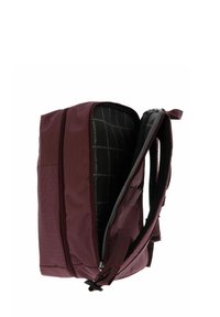 Sac à dos bordeaux avec un compartiment principal ouvert, des bretelles rembourrées et une doublure intérieure imprimée avec le nom de la marque sur fond blanc.