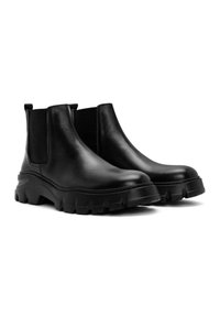 Botas de tobillo de cuero negro con un acabado texturizado, paneles laterales elásticos y una suela gruesa y resistente para tracción. Superficie lisa con costuras mínimas.