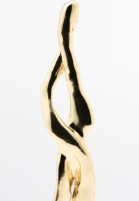 Scultura astratta in metallo dorato con curve lisce ed allungate e una superficie riflettente, caratterizzata da un design intrecciato e priva di una base visibile.