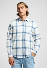 Camisa de cuadros azul y blanca con cierre de botones, dos bolsillos en el pecho y un dobladillo redondeado. Hecha de un tejido suave con un diseño casual.