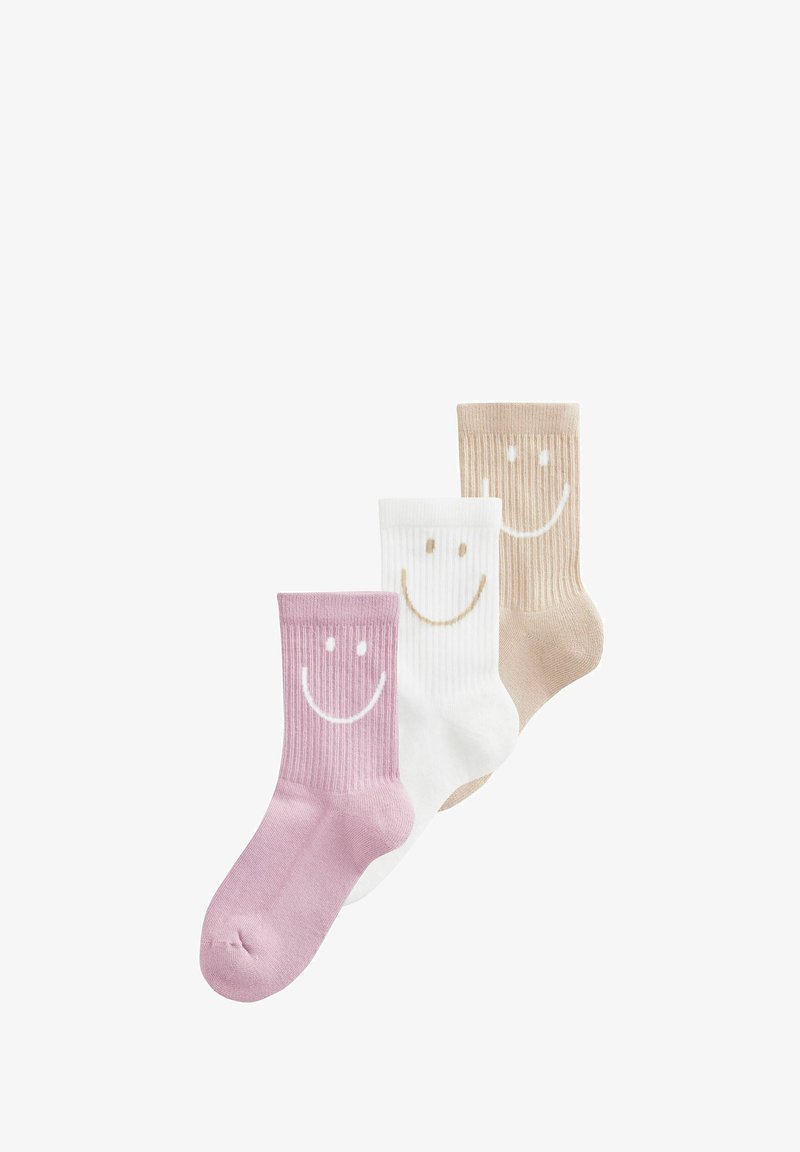 Trois chaussettes montantes côtelées en rose, blanc et beige, chacune avec un grand visage souriant près du haut.