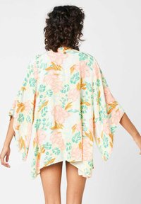 Cubierta estilo kimono floral en tejido suave y ligero. Presenta flores en tonos durazno y verde sobre un fondo amarillo claro. Corte holgado y mangas tipo murciélago.