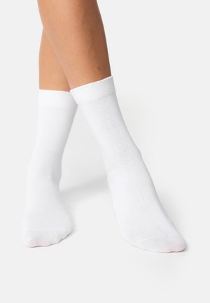 Chaussettes en coton blanches avec un revers côtelé, texture lisse et longueur cheville. Ne présente aucune marque ni motif visible.