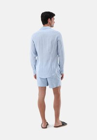 Hellblau gestreiftes Hemd und passende Shorts, aus einem weichen Stoff gefertigt. Das Hemd hat lange Ärmel mit Manschetten, und die Shorts sind kurz.