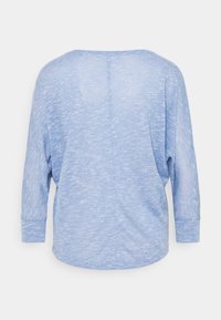 Haut en tricot bleu clair à manches longues avec un large décolleté et une coupe légèrement ample, vu de dos sur un fond blanc uni.