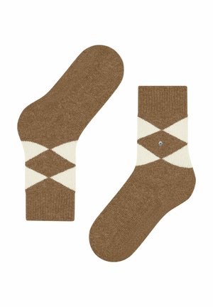 Un paio di calze a maglia marroni con motivo a rombi bianchi attorno alla caviglia su uno sfondo bianco.