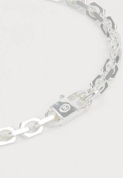 Silver chain bracelet featuring interlinked hexagonal and oval-shaped links, with a clasp detail for secure fastening.
