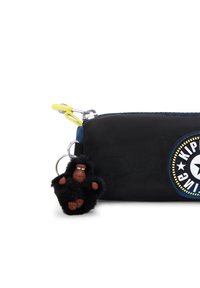 Svart tygpåse med en gul dragkedja, blå kant och en rund logotyp. Innehåller en fluffig svart gorilla nyckelring som är fäst.