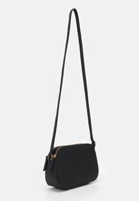 Czarna torba na ramię o gładkiej fakturze, owalnym kształcie i złotych zamkach błyskawicznych. Posiada długi, regulowany pasek do wszechstronnego noszenia.