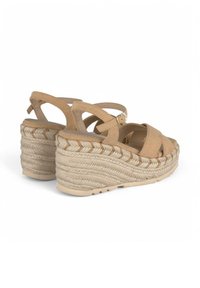 Sandalias de cuña de ante beige con una plataforma de yute trenzado, diseño de tiras cruzadas, hebilla ajustable en el tobillo y parte inferior texturizada.