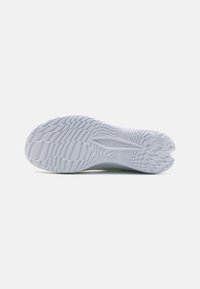 Semelle de chaussure en caoutchouc blanc avec un motif de tread texturé. Présente une rainure centrale et "UNDER ARMOUR" embossé sur le côté.