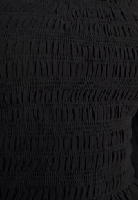 Černá tkanina s vertikálním sháněním s texturovaným, nashromážděným designem. Více řad elastického prošití vytváří výrazné, zvlněné vzory.