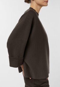 Brązowy, luźny sweter o teksturowanej powierzchni, z żebrowanymi mankietami i falistym dekoltem. Zaprojektowany z luźnym krojem i opuszczonymi szwami na ramionach.