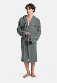 Accappatoio grigio in cotone con cappuccio, cintura frontale e tasche laterali. Presenta un logo sul petto e un motivo decorativo sulle maniche.