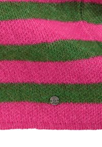 Nahaufnahme von gestricktem Stoff mit abwechselnd rosa und grünen horizontalen Streifen und einem kleinen runden Metallschild, das befestigt ist.