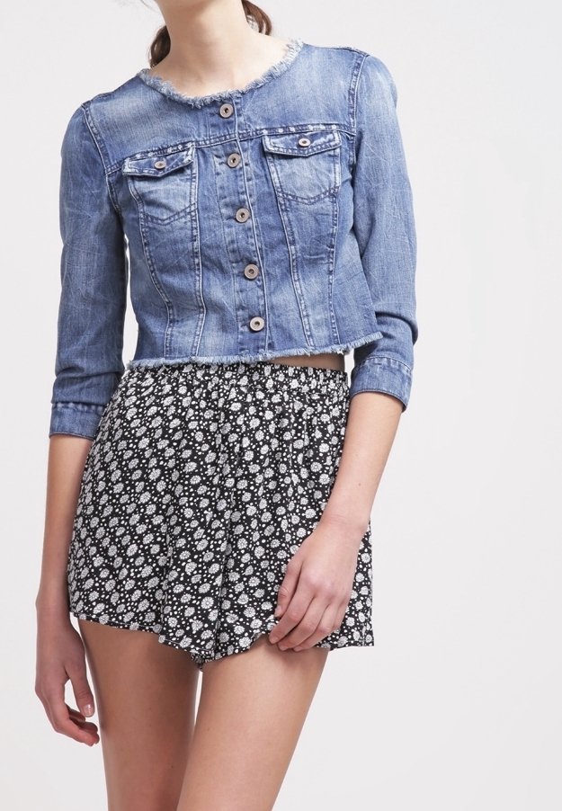 Kurtka dżinsowa o skróconym fasonie, z zapięciem na guziki i dwoma przednimi kieszeniami, zestawiona z czarnymi szortami w kwiatowy wzór.