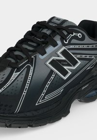 Μαύρο και γκρι αθλητικό παπούτσι New Balance για τρέξιμο με μαύρα κορδόνια, λευκές λεπτομέρειες και μαλακό πάτο με ορατή αερόσολα.