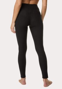 Zwarte leggings gemaakt van een gladde, rekbare stof, met een hoge taille en een aansluitend ontwerp, zonder zichtbare naden of patronen.