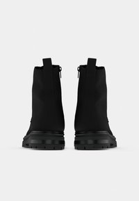Černé kotníkové boty s matným povrchem, s designem do vyššího střihu, zadním zipem a odolnými gumovými podrážkami s robustním vzorem.
