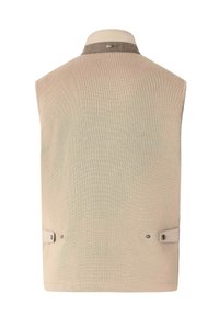 Gilet beige sans manches avec col montant, bordure en suède au niveau du cou et languettes réglables avec boutons-pression de chaque côté à l'arrière.