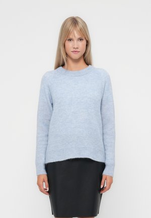Lys blå, myk strikkegenser med rund hals og ribbede mansjetter, brukt over et svart skinnskjørt med rett silhuett.