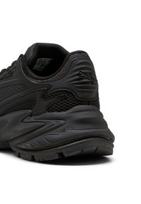 Tomaia della sneaker nera Puma con un tallone in mesh testurizzato e sovrapposizioni sintetiche, logo in rilievo sulla collare imbottito e suola in gomma spessa e testurizzata.