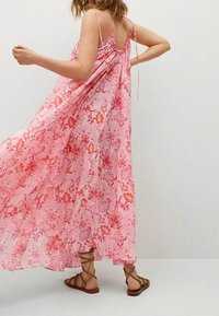 Maxi-mekko vaaleanpunaisena kukkakuviolla, kevyttä kangasta, olkaimeton malli ja rutistettu selkäosa. Yhdistetty ruskeisiin nyörisaappaisiin.