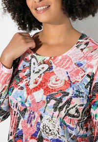 Buntes Langarmshirt mit abstrakten Mustern in Pink, Rot, Blau und Grün, durchsetzt mit Paillettenakzenten im gesamten Design.