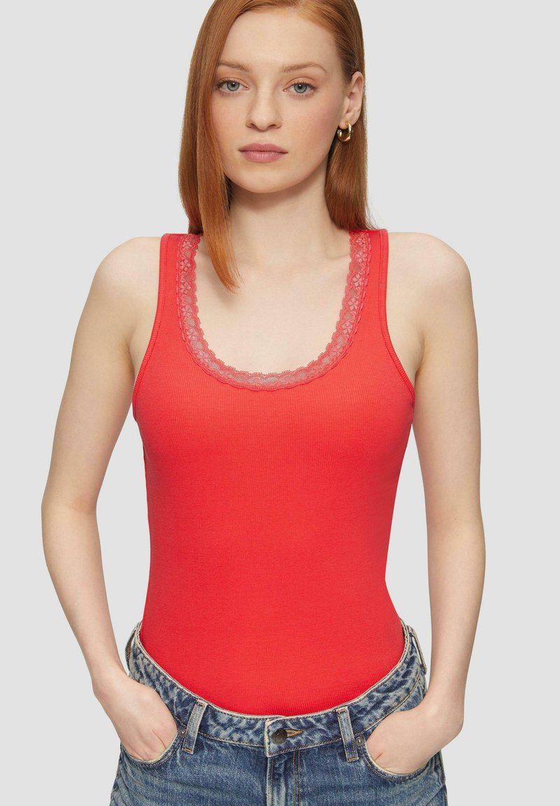 Rode tanktop met een geribbelde textuur en een scoopdecollté met kantafwerking, gecombineerd met high-waisted, vervagende denimshorts.