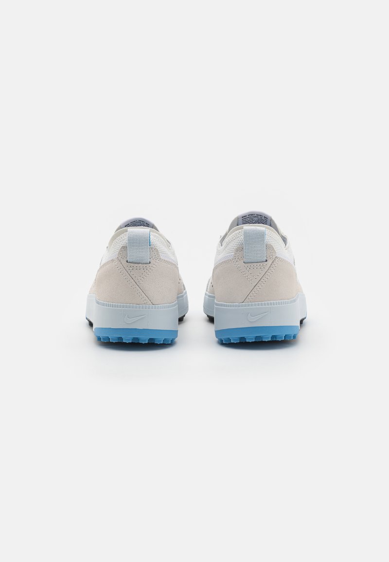 Zapatillas de ante blancas y gris claro con acentos azules, que cuentan con una superficie texturizada, un talón acolchado y un logotipo distintivo en el lateral.